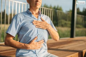 Man practicing mindful breathing outdoors with one hand on his chest and the other on his abdomen, symbolizing focus and calm in recovery.