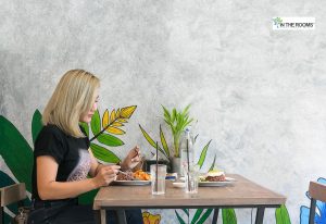 Woman sitting alone at a restaurant table, enjoying a meal and practicing self-care in recovery.