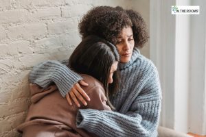 Two women sitting close together, one comforting the other with a gentle embrace, conveying empathy and emotional support during a difficult moment.