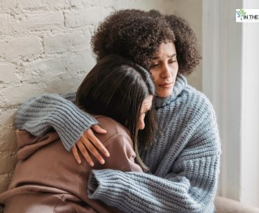Two women sitting close together, one comforting the other with a gentle embrace, conveying empathy and emotional support during a difficult moment.