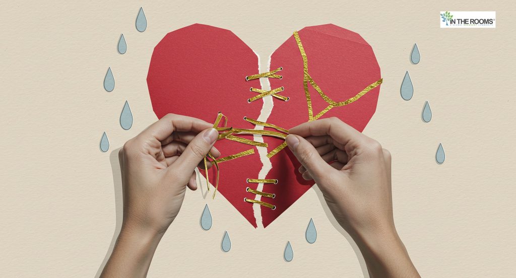 Hands mending a torn paper heart with golden threads, symbolizing emotional healing and rebuilding life after hardship.