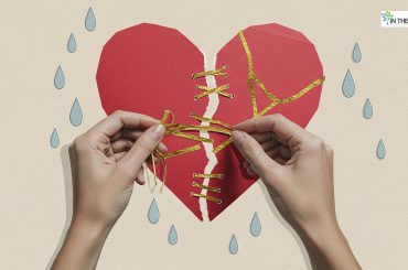 Hands mending a torn paper heart with golden threads, symbolizing emotional healing and rebuilding life after hardship.