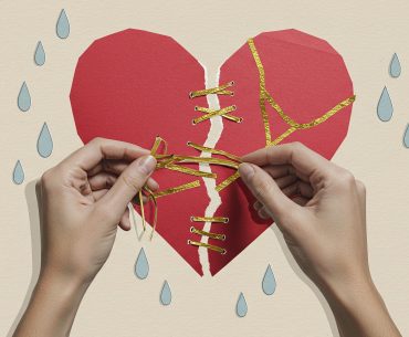 Hands mending a torn paper heart with golden threads, symbolizing emotional healing and rebuilding life after hardship.