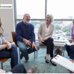 People sitting in a support group circle, smiling and sharing openly during a recovery meeting.