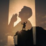 A silhouette of a person praying overlaid with another image of a person standing triumphantly on a mountain peak, symbolizing inner strength and spiritual awakening in recovery.