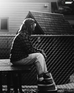A person sitting alone on a bench, looking away thoughtfully in a quiet outdoor space, symbolizing reflection, guilt, and emotional healing in recovery.